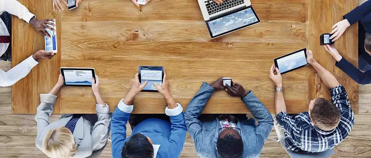 Employees sitting at a table with tablets and phones